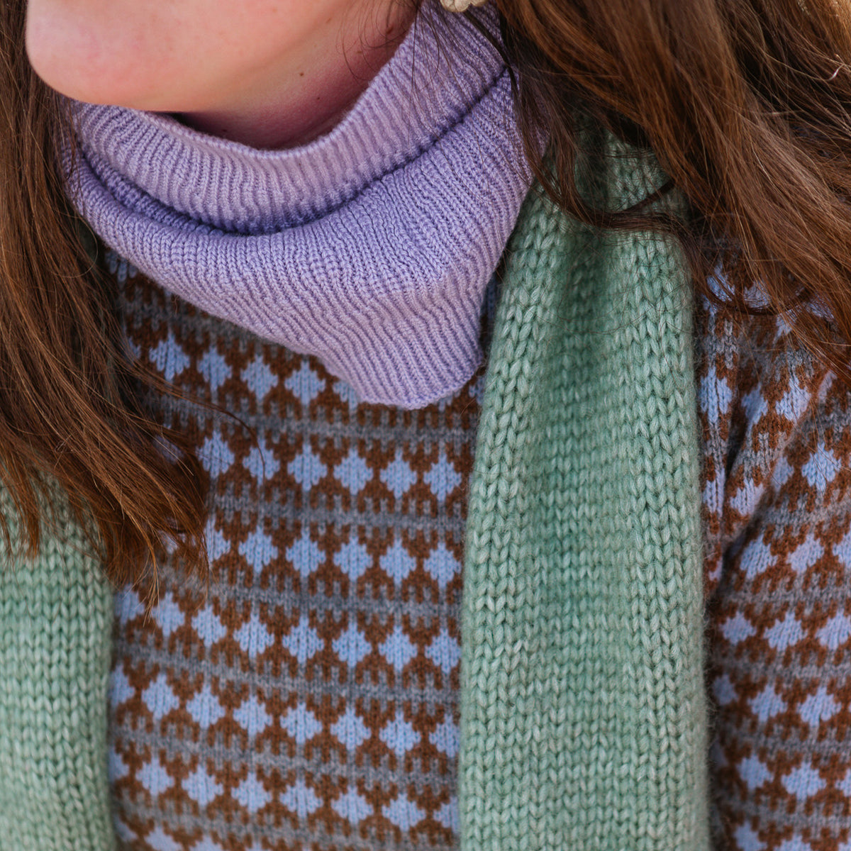 Close-up of a person wearing a green knitted sweater with a patterned design.