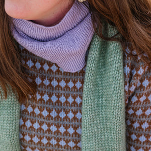 Close-up of a person wearing a green knitted sweater with a patterned design.
